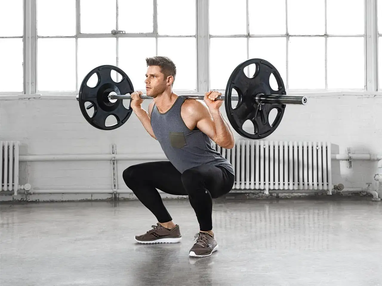 Mężczyzna wykonuje przysiad ze sztangą, element kluczowy w każdym powerlifting plan treningowy.