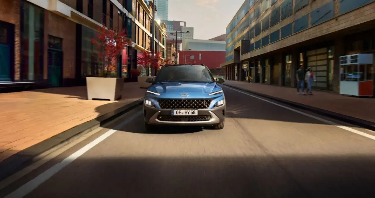 Niebieski Hyundai Kona Hybrid jedzie ulicą w mieście.