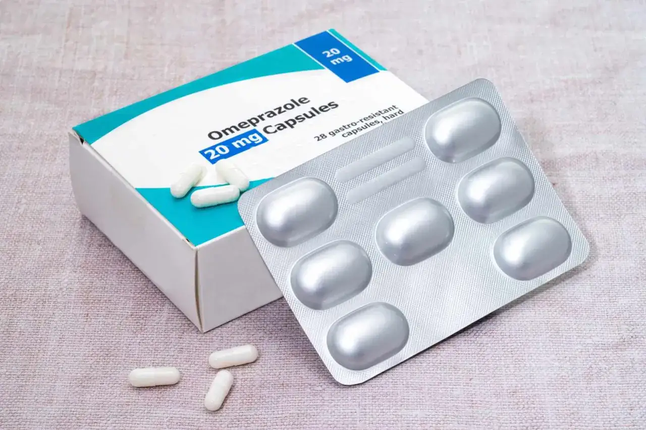 Opakowanie leku Omeprazole 20 mg kapsułki i blister z lekami. Kilka kapsułek leży obok pudełka.