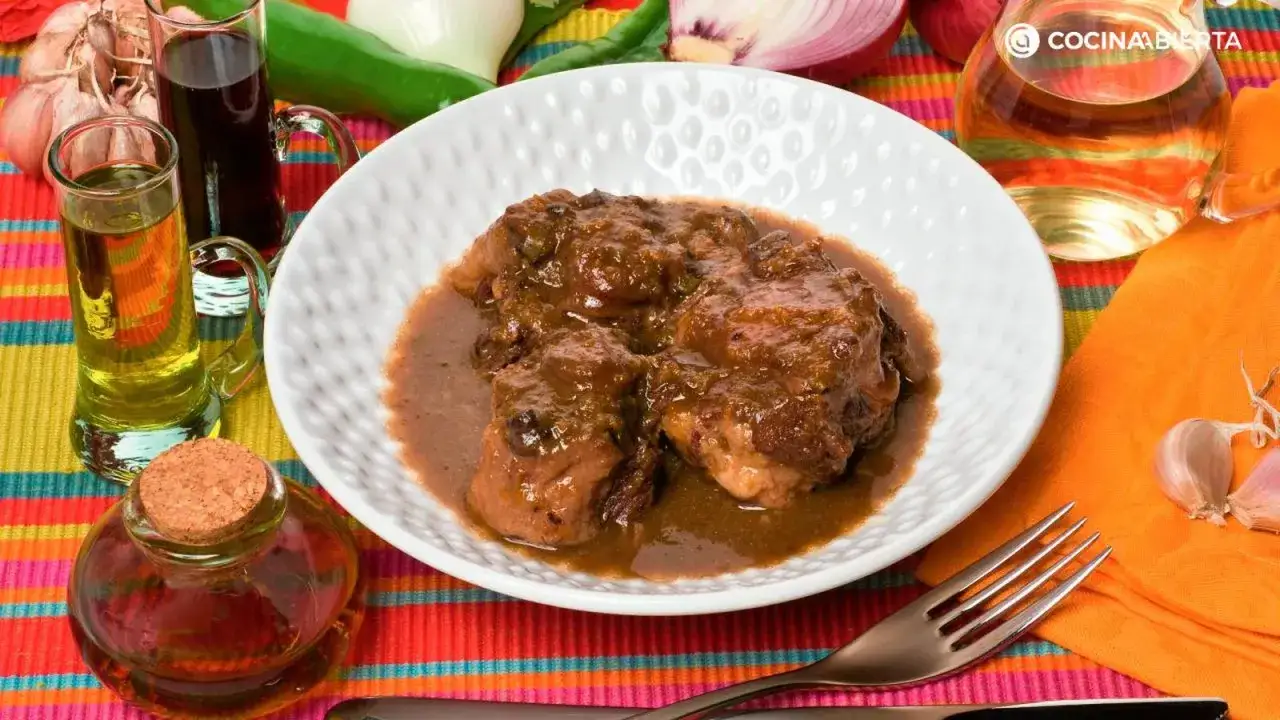 Delicioso rabo de cerdo estofado en salsa, acompa&ntilde;ado de ingredientes frescos como ajos, cebolla y pimientos.