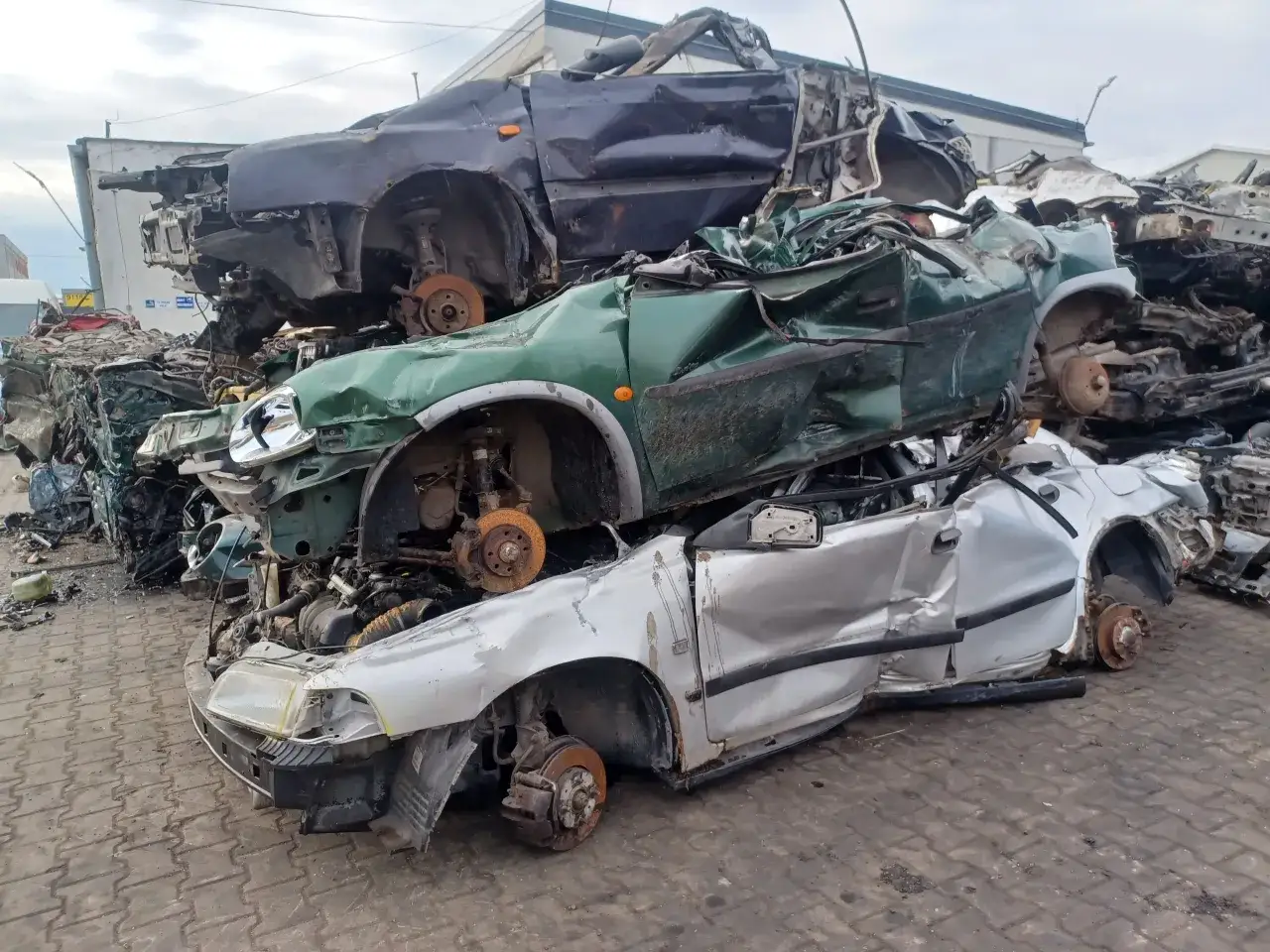 Złomowisko samochodowe z pogniecionymi autami. Widać, jak sprzedać auto na części, gdy jest w takim stanie.