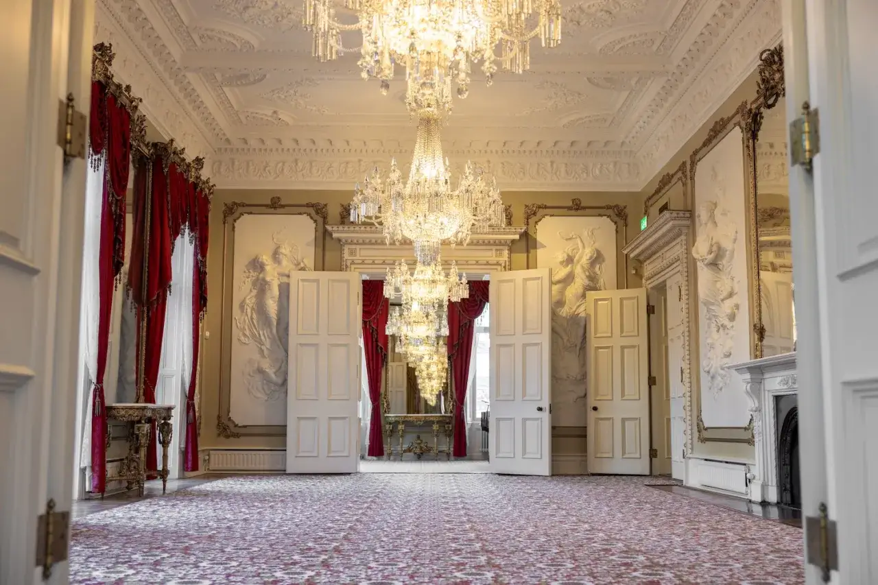 Ett elegant rum i Dicksonska palatset med kristallkronor, röda draperier och konstnärliga väggreliefer.