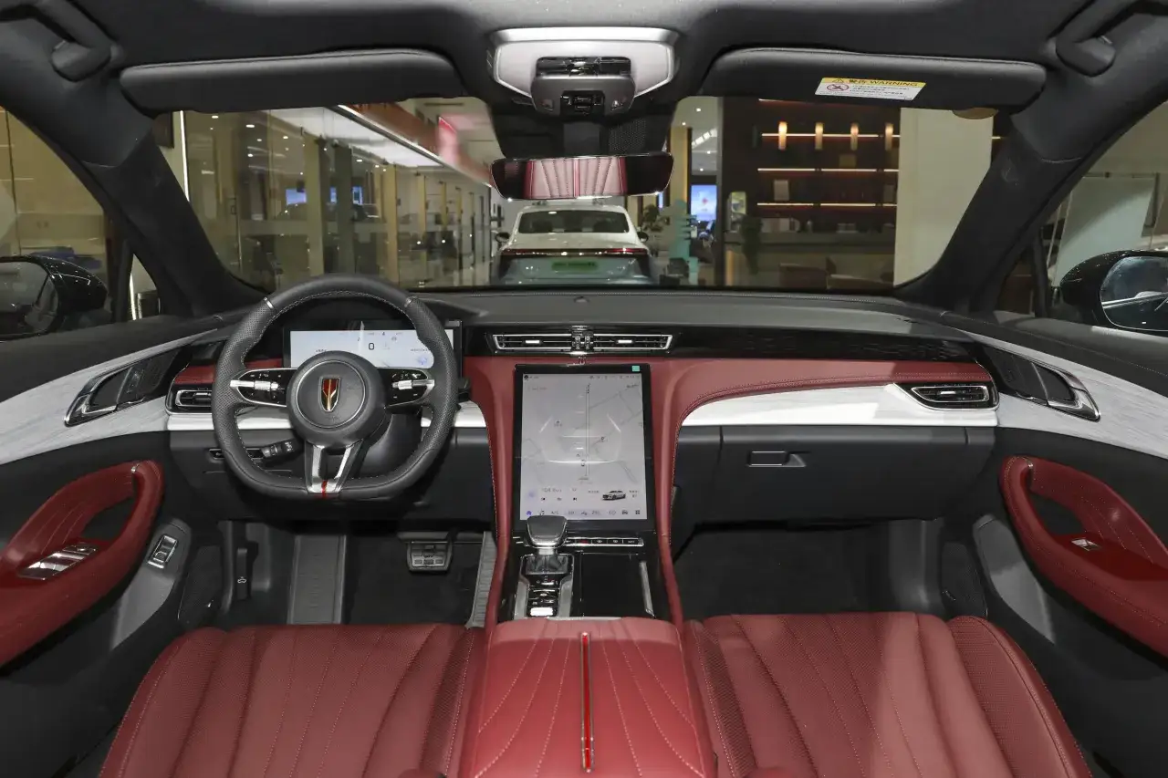Wnętrze Hongqi H5 z czerwonymi skórzanymi fotelami i nowoczesnym panelem sterowania.