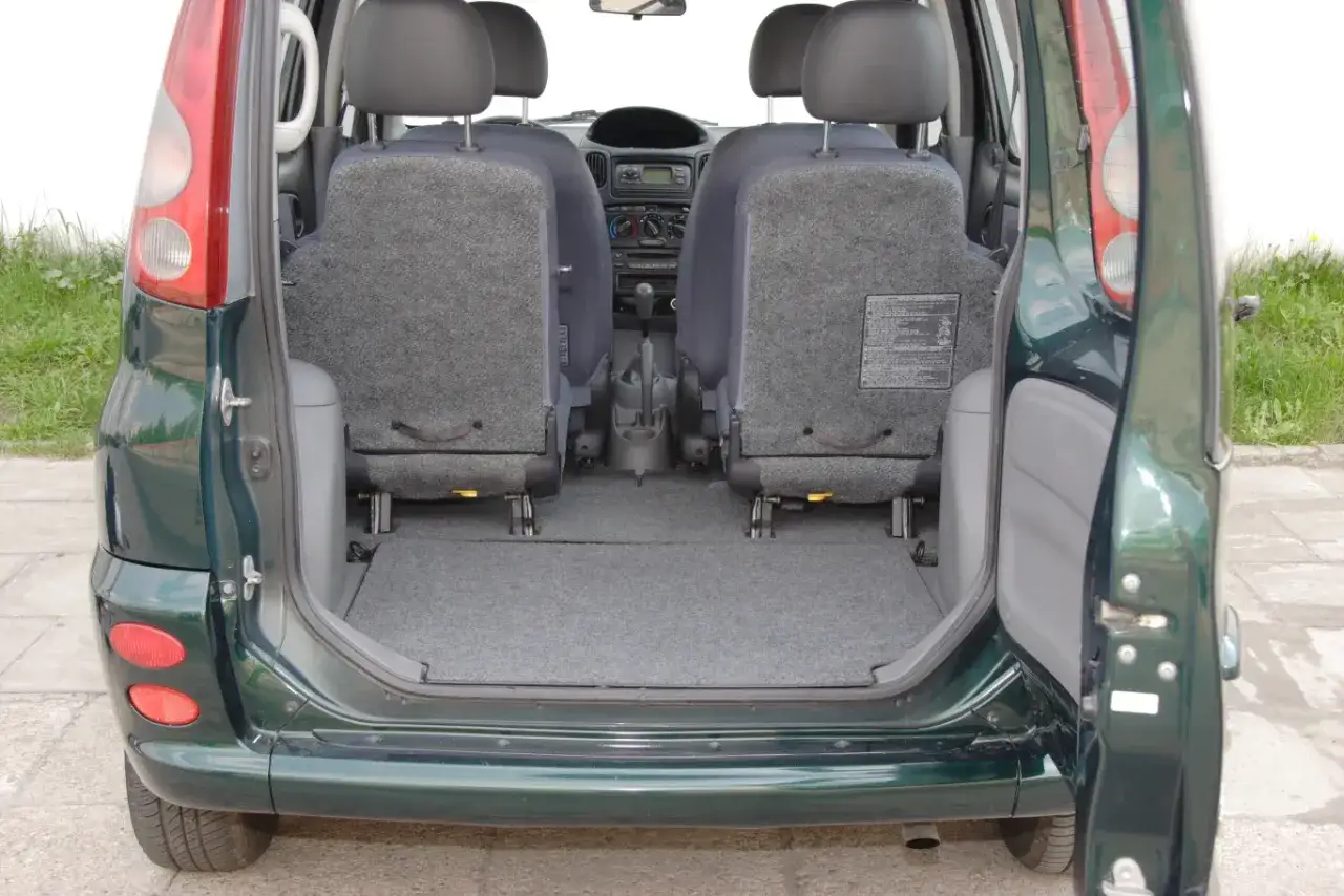 Wnętrze zielonego Toyota Yaris Verso z rozłożonymi tylnymi siedzeniami, tworzącymi dużą przestrzeń bagażową.