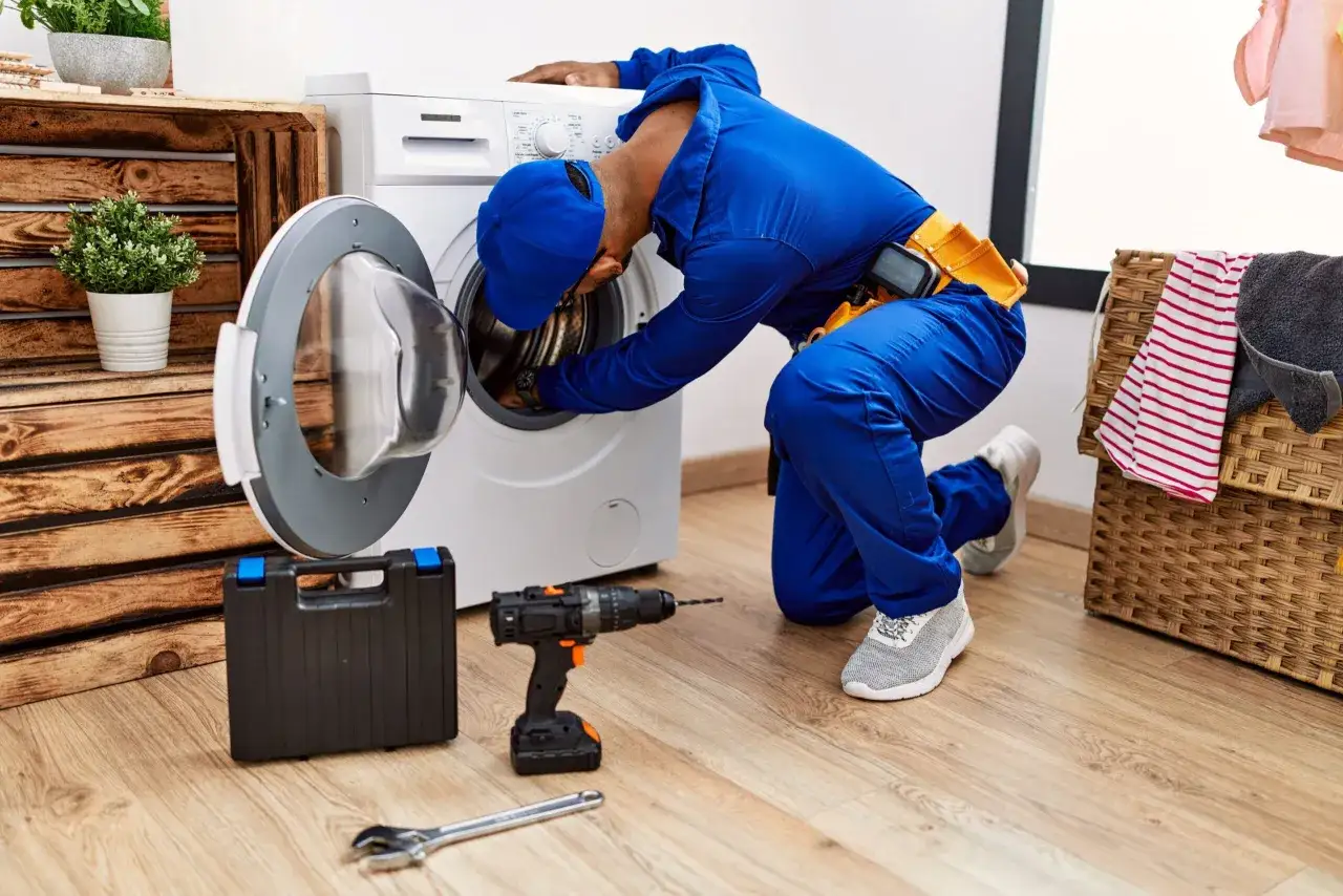 Un technicien répare une machine à laver. Si le produit est défectueux, il y aura un remplacement ou un remboursement.