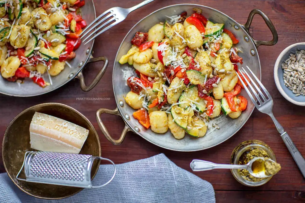Pyszne gnocchi z pesto, papryką, cukinią i suszonymi pomidorami, posypane parmezanem i słonecznikiem.