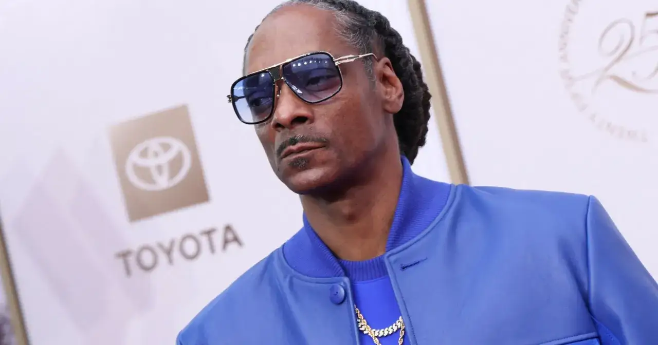 Snoop Dogg w niebieskiej kurtce i okularach, jakby szykował się do kolejnych filmów.