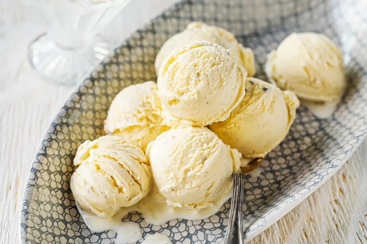 Plusieurs boules de glace vanille maison fondent doucement sur une assiette d&eacute;cor&eacute;e. Un d&eacute;lice cr&eacute;meux et parfum&eacute;.