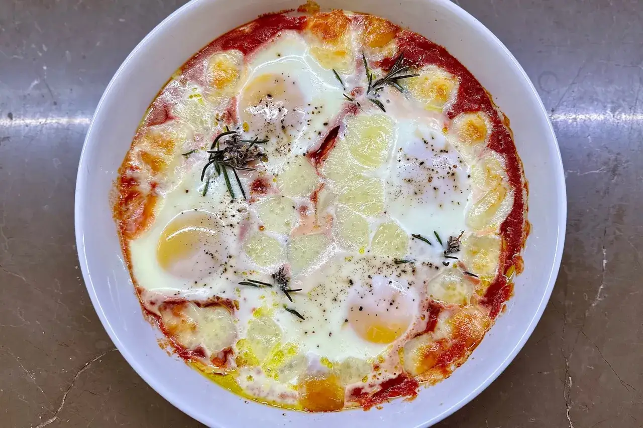 Uova alla contadina in teglia, con pomodoro, formaggio filante e rosmarino. Un piatto rustico e saporito, perfetto per una colazione o un brunch.