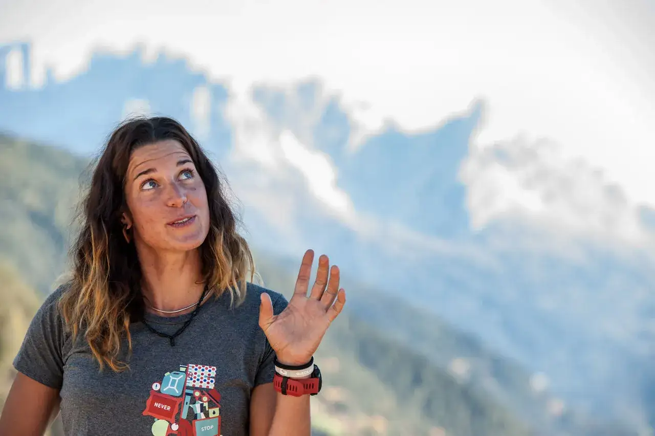 Tamara Lunger blickt nachdenklich in den Himmel, die Hand erhoben, als w&uuml;rde sie die n&auml;chste Herausforderung planen.