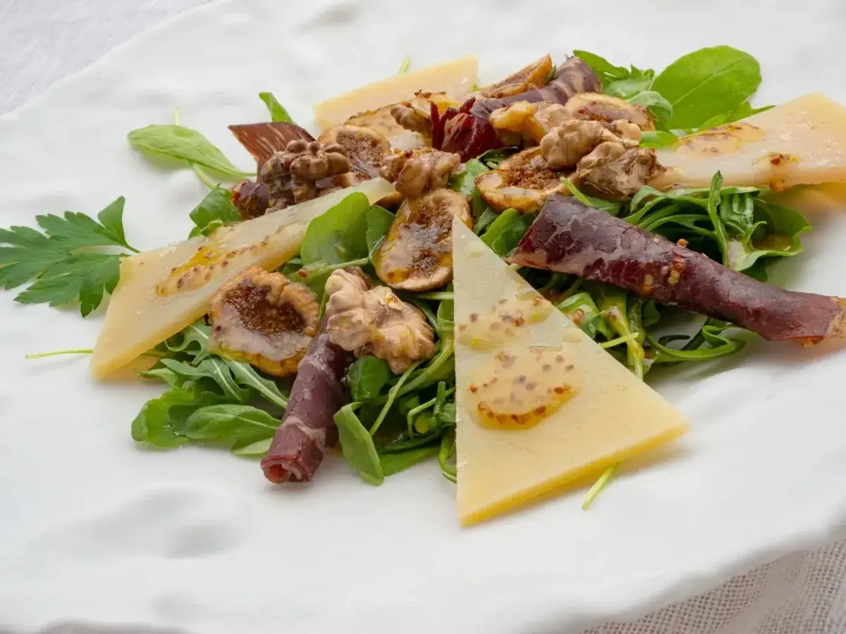 Deliciosa ensalada de cecina con higos, nueces, queso y aderezo de mostaza sobre rúcula fresca.