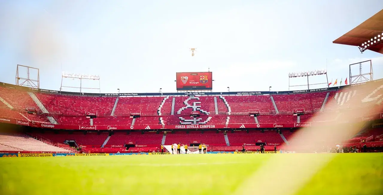 Puste trybuny stadionu Sevilla, z herbem klubu na środku i napisem 