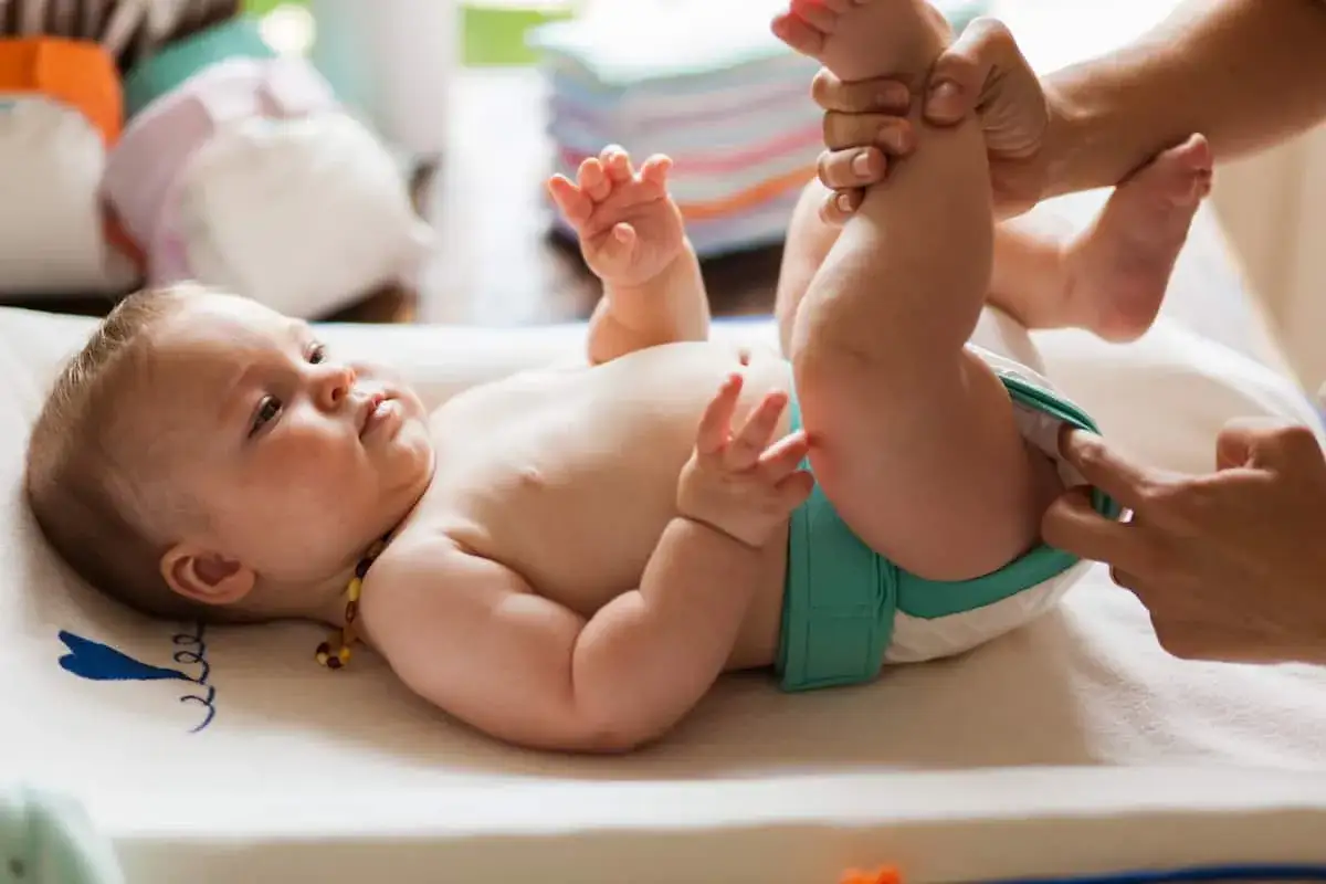Un neonato di 1 mese, sdraiato su un fasciatoio, mentre gli cambiano il pannolino. Quante volte fa la cacca un neonato di 1 mese? Dipende!