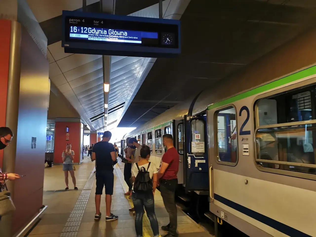 Pasażerowie czekają na peronie 4. Wyświetlacz informuje o opóźnieniu pociągu do Gdyni Głównej, co sugeruje awarię taboru.