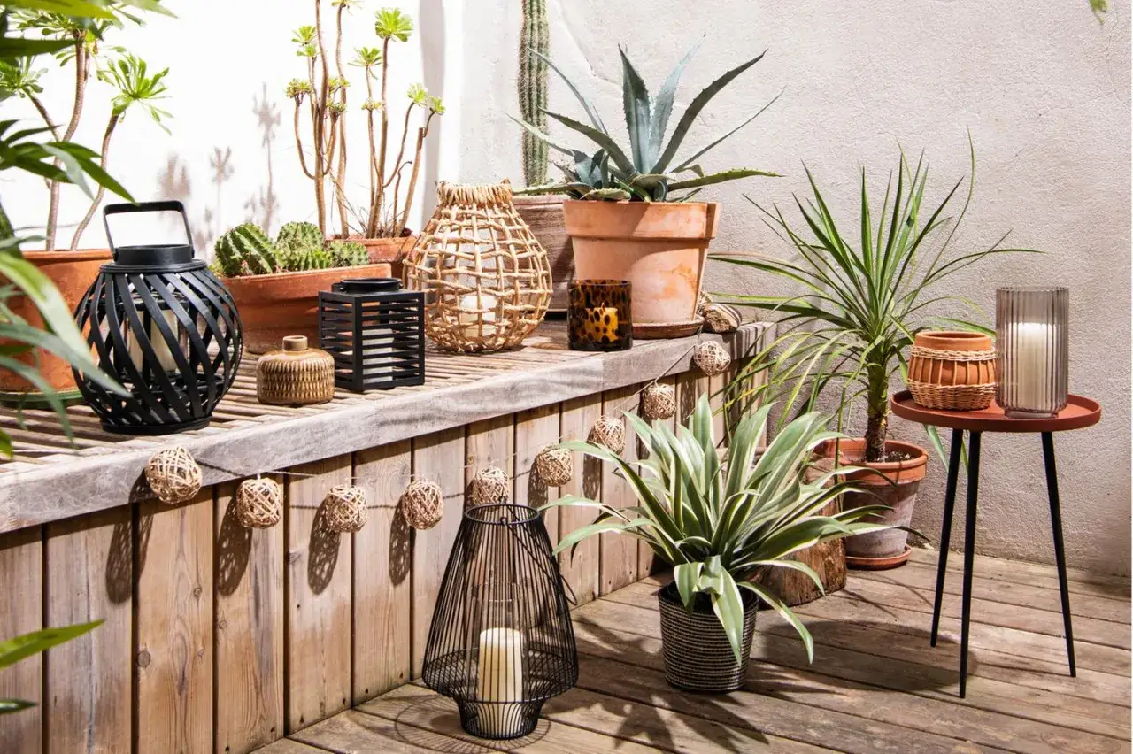 Gem&uuml;tliche boho balkon ideen mit Laternen, Pflanzen und Deko-Kugeln aus Naturmaterialien.