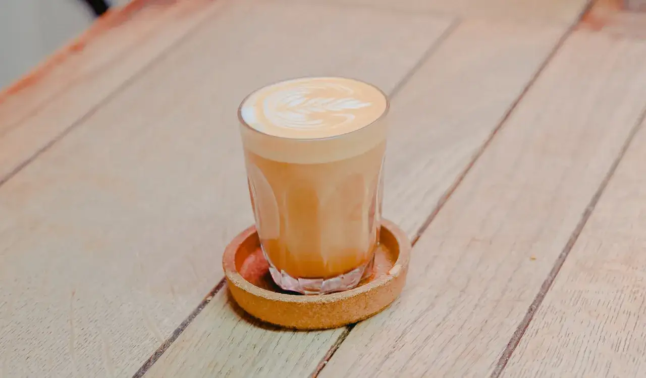 En vacker flat white kaffe med lattekonst på en träyta.