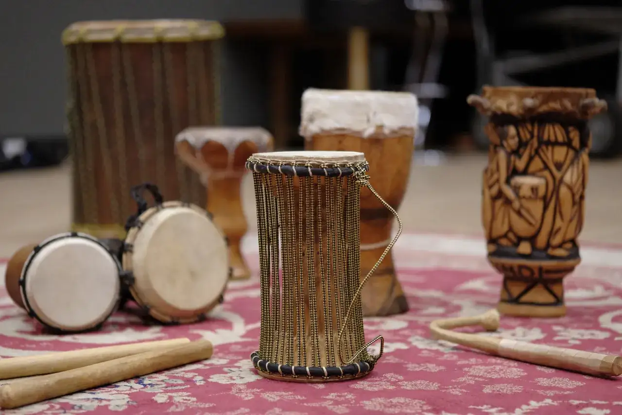 Ensemble de percussions africaines, incluant des djemb&eacute;s et un tambour sculpt&eacute;, pr&ecirc;ts pour une session musicale.