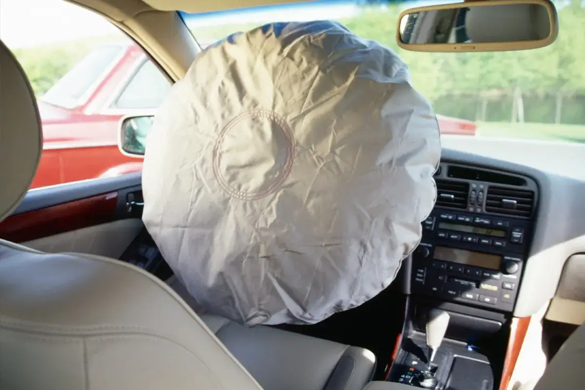 Interno auto con airbag lato guida dispiegato. Il ripristino airbag obbligatorio è fondamentale per la sicurezza.