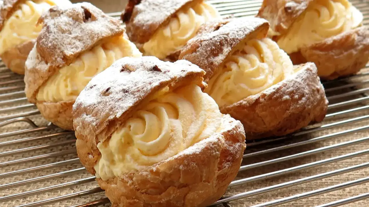 Bignè ripieni di crema, spolverati di zucchero a velo. La pasta choux ricetta originale è un classico intramontabile.