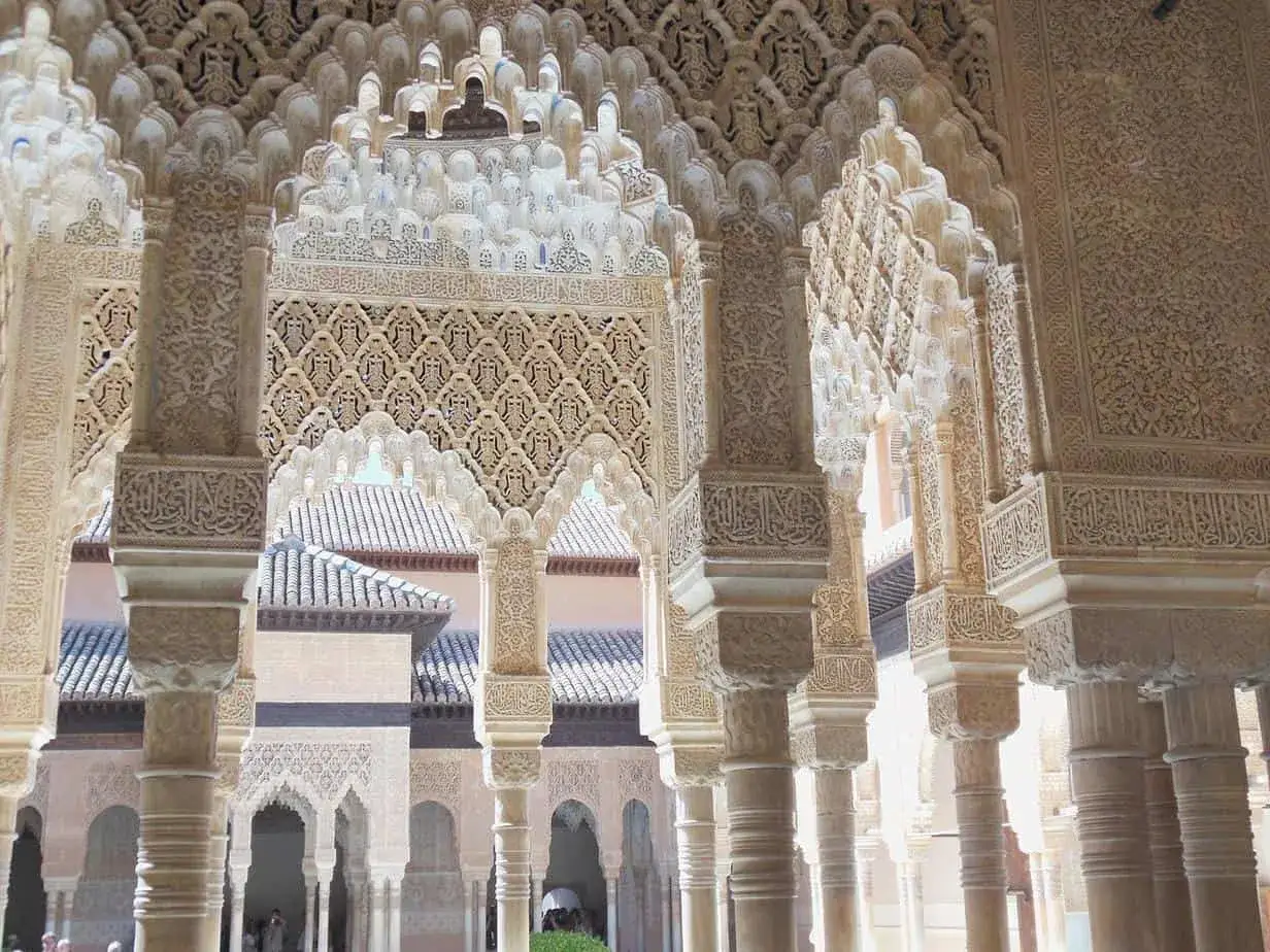 Detailreiche S&auml;ulen und B&ouml;gen der Alhambra Moschee, mit filigranen Ornamenten und Kalligraphie. Ein Blick in den Innenhof.