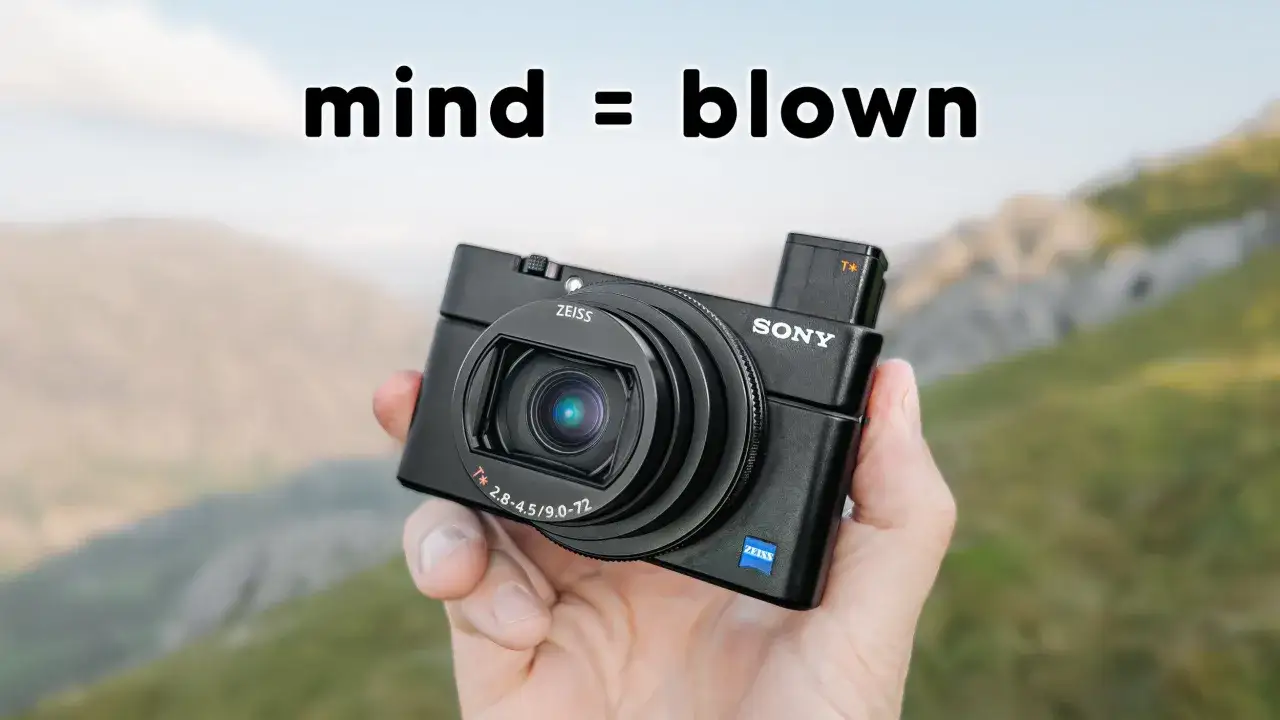 Dłoń trzyma aparat Sony RX100 VIII na tle górskiego krajobrazu. Napis 