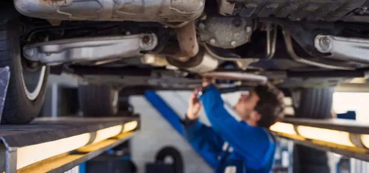 Mechanik pracuje pod samochodem, sprawdzając układ kierowniczy. To właśnie maglownica w samochodzie odpowiada za precyzyjne skręcanie.