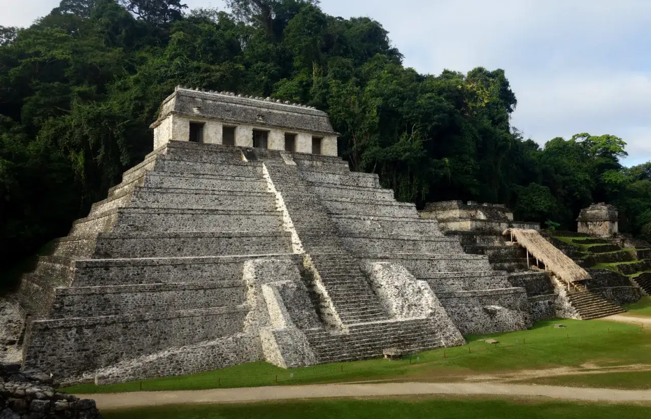 Majest&auml;tische Maya-Ruinen, eine steinerne Pyramide mit Treppen, ragt vor &uuml;ppigem Dschungel auf.