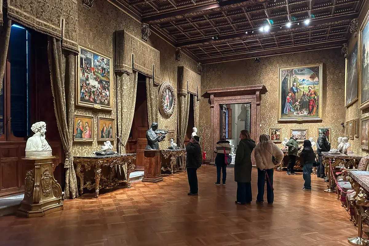 Wnętrze Galerii Doria Pamphilj z obrazami i rzeźbami, zwiedzający podziwiają dzieła sztuki.