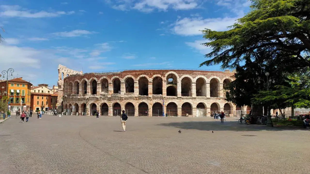 La majestueuse **Arène de Vérone** se dresse fièrement sous un ciel bleu, ses arches antiques invitant à un voyage dans le temps.