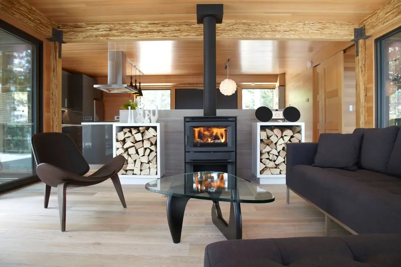 Salon moderne avec po&ecirc;le &agrave; bois cr&eacute;pitant, canap&eacute; confortable et bois qui ne br&ucirc;le pas empil&eacute; pour le chauffage.
