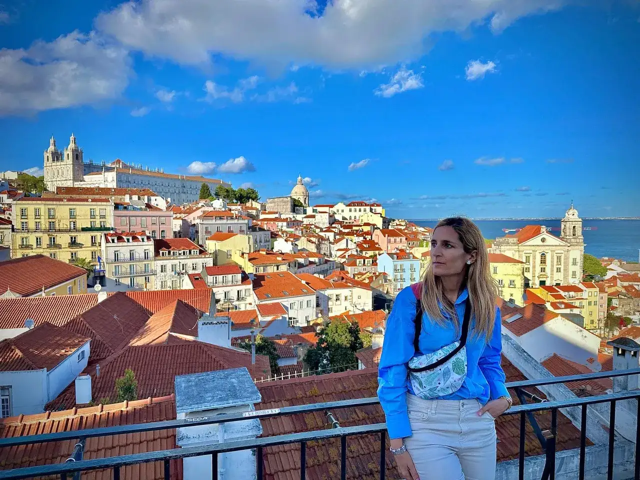 Mujer con bolsa cruzada admira el paisaje urbano de Lisboa, ideal para saber qué ver en Lisboa en 3 días.