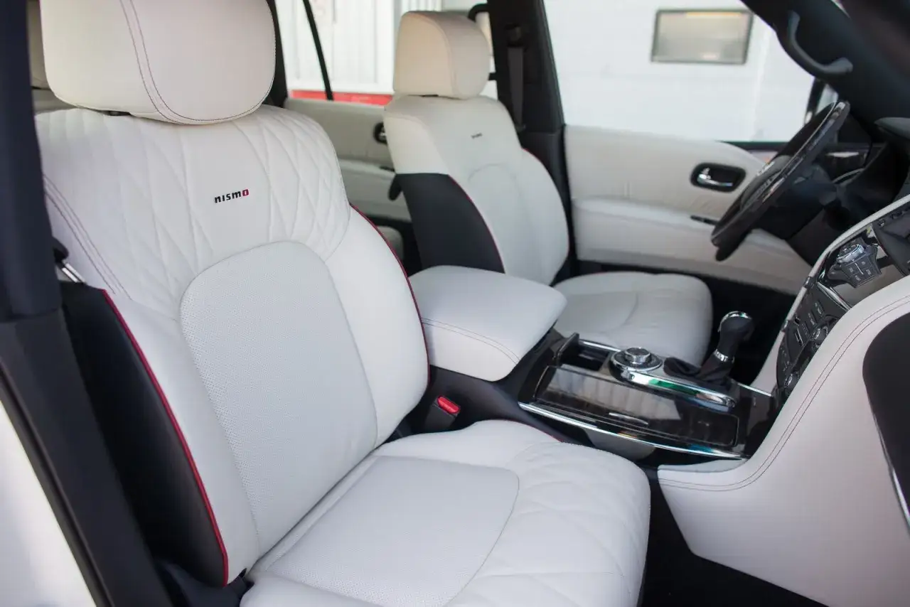 Wnętrze Nissan Patrol Nismo: białe, pikowane fotele z czerwonymi akcentami i logo Nismo. Luksus i sportowy charakter.