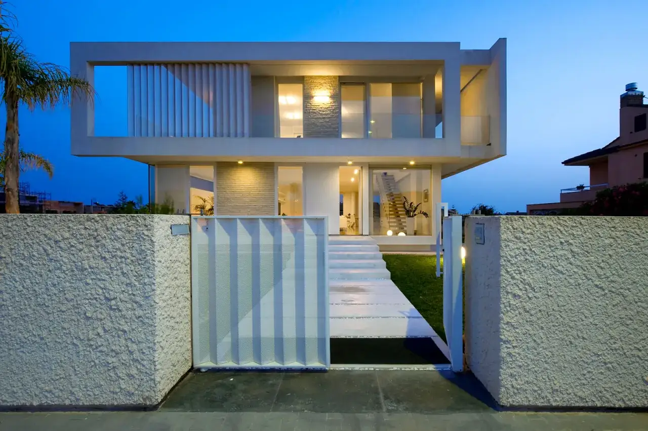 Un'elegante villa con un design minimalista, un esempio di case moderne esterno. La facciata è illuminata da luci soffuse, creando un'atmosfera accogliente.