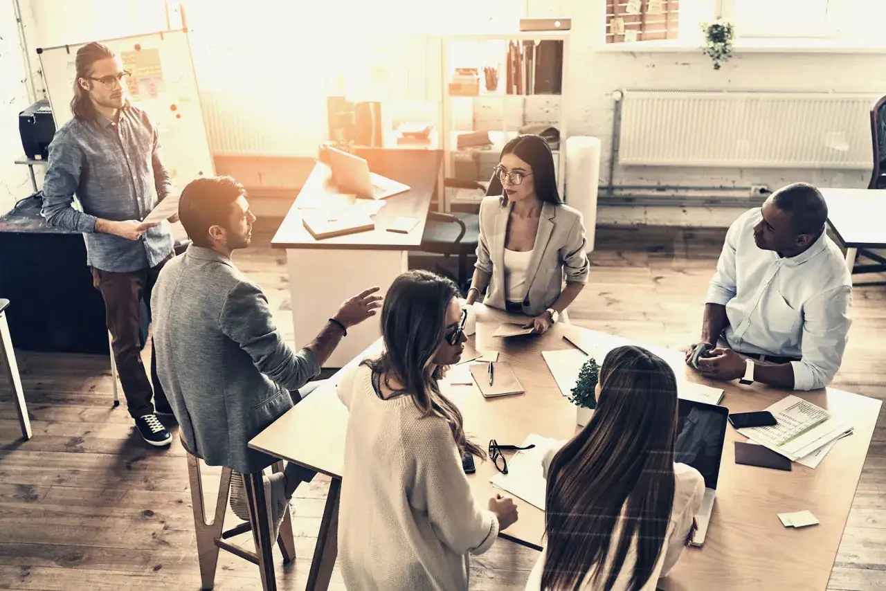 Team meeting discussing DEI graduate certificate. Diverse professionals collaborate in a bright, modern office space.