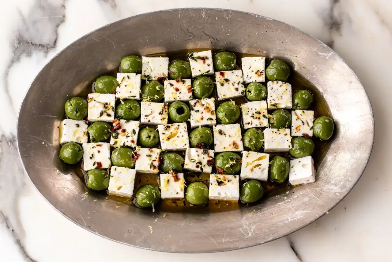 Gr&uuml;ne Oliven und gew&uuml;rfelter Feta in &Ouml;l mariniert, mit Kr&auml;utern und Gew&uuml;rzen bestreut. Ein k&ouml;stlicher Appetizer zum Oliven essen.