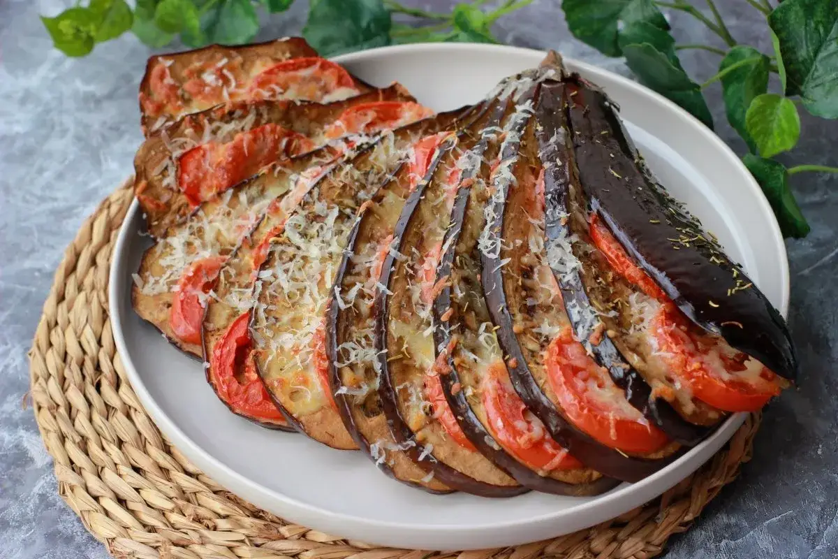 Berenjenas a la parmesana, un plato italiano con berenjenas horneadas, tomate y queso rallado, listo para disfrutar.