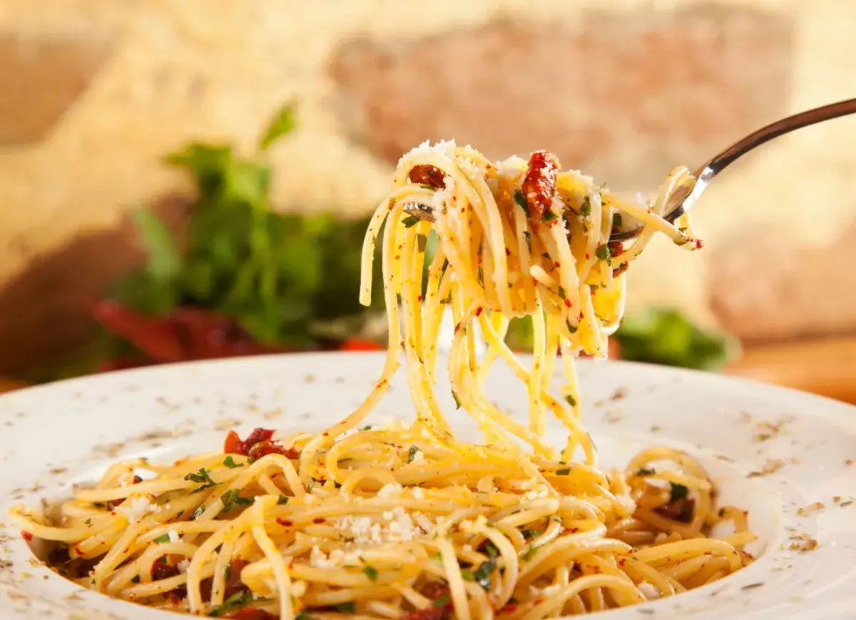 Widok z bliska na talerz spaghetti z widocznymi kawałkami suszonych pomidorów i ziół. Idealne przyprawy do spaghetti, które podkreślą smak dania.