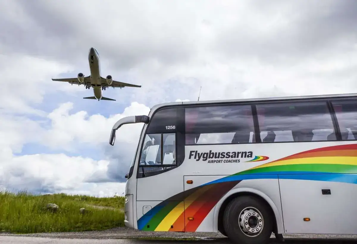 Samolot wznosi się nad autokarem Flygbussarna, który czeka na pasażerów na lotnisko Nyo.