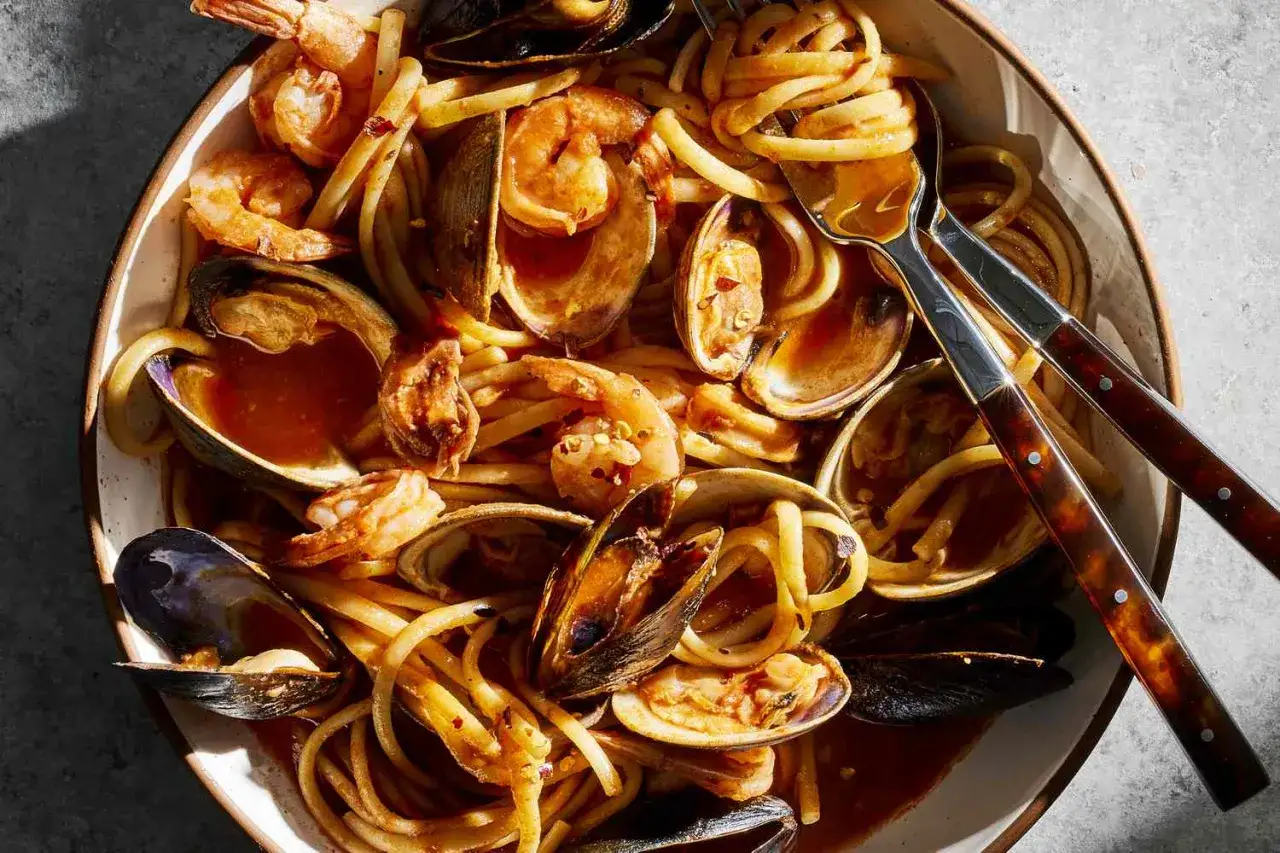 Pyszne spaghettini z krewetkami i małżami w sosie pomidorowym, posypane płatkami chili.