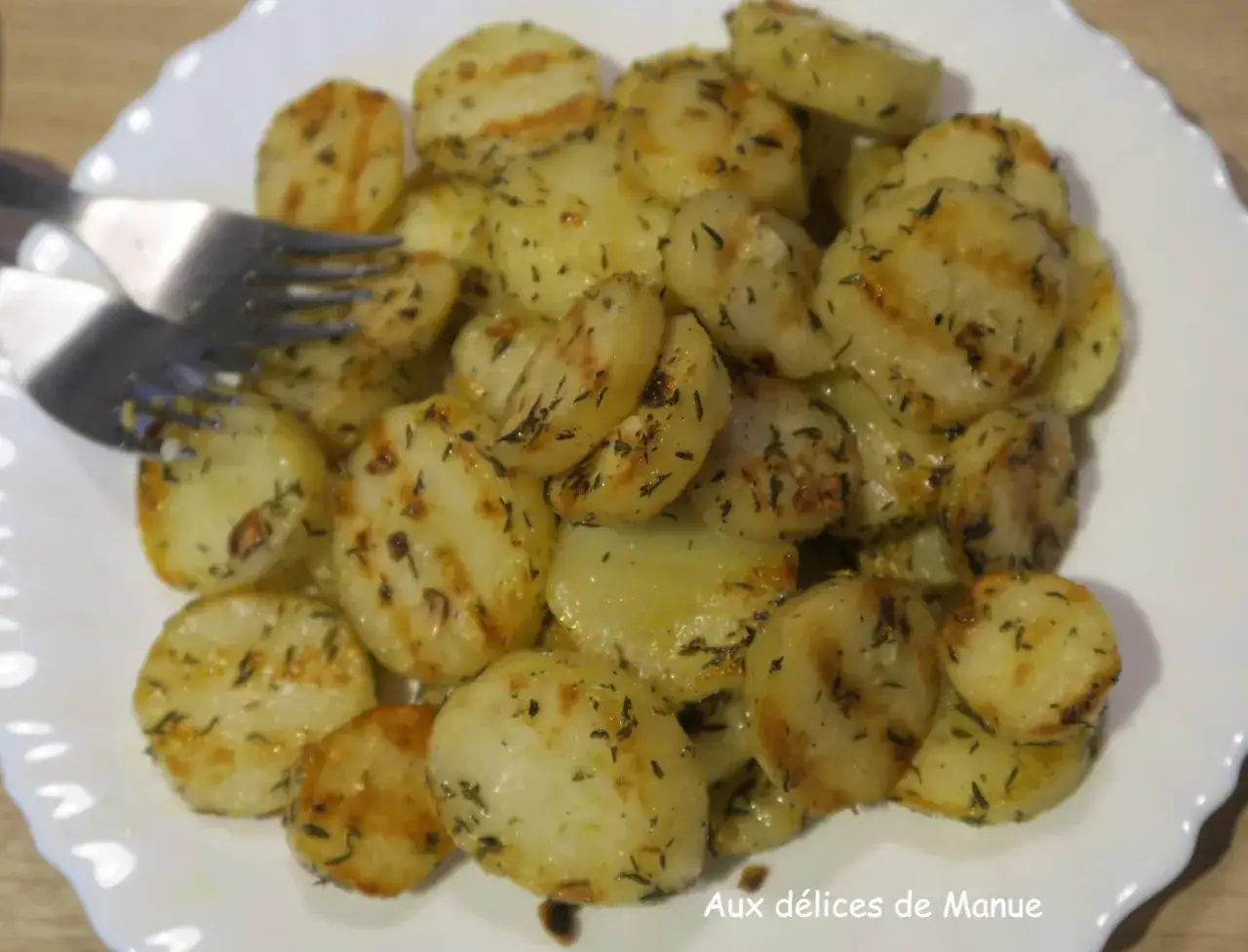 Pommes de terre plancha coupées en rondelles, dorées et parsemées d'herbes. Deux fourchettes sont prêtes à déguster ce plat savoureux.