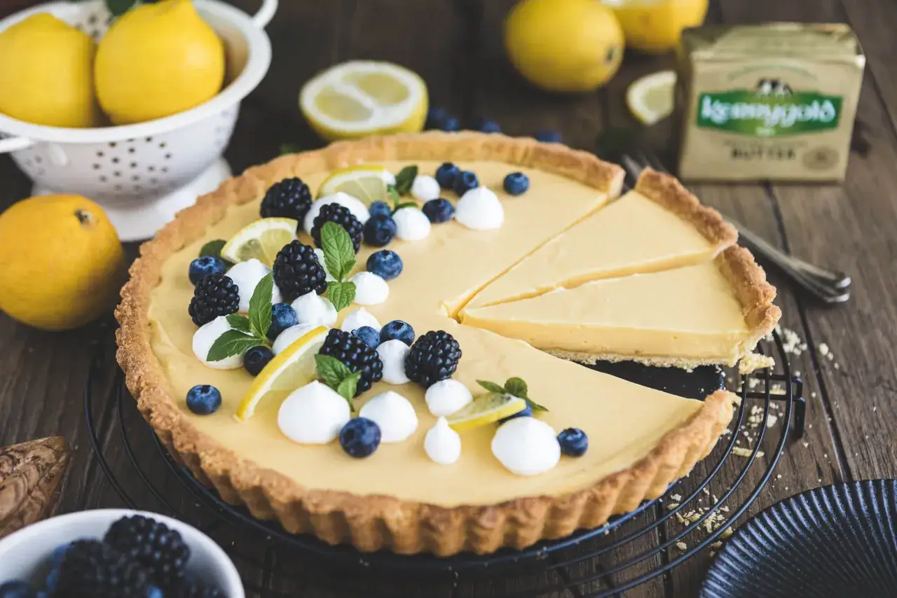 Zitronentarte rezept: Cremige Tarte mit frischen Beeren, Minze und Zitronenspalten. Ein Genuss für jeden Anlass!
