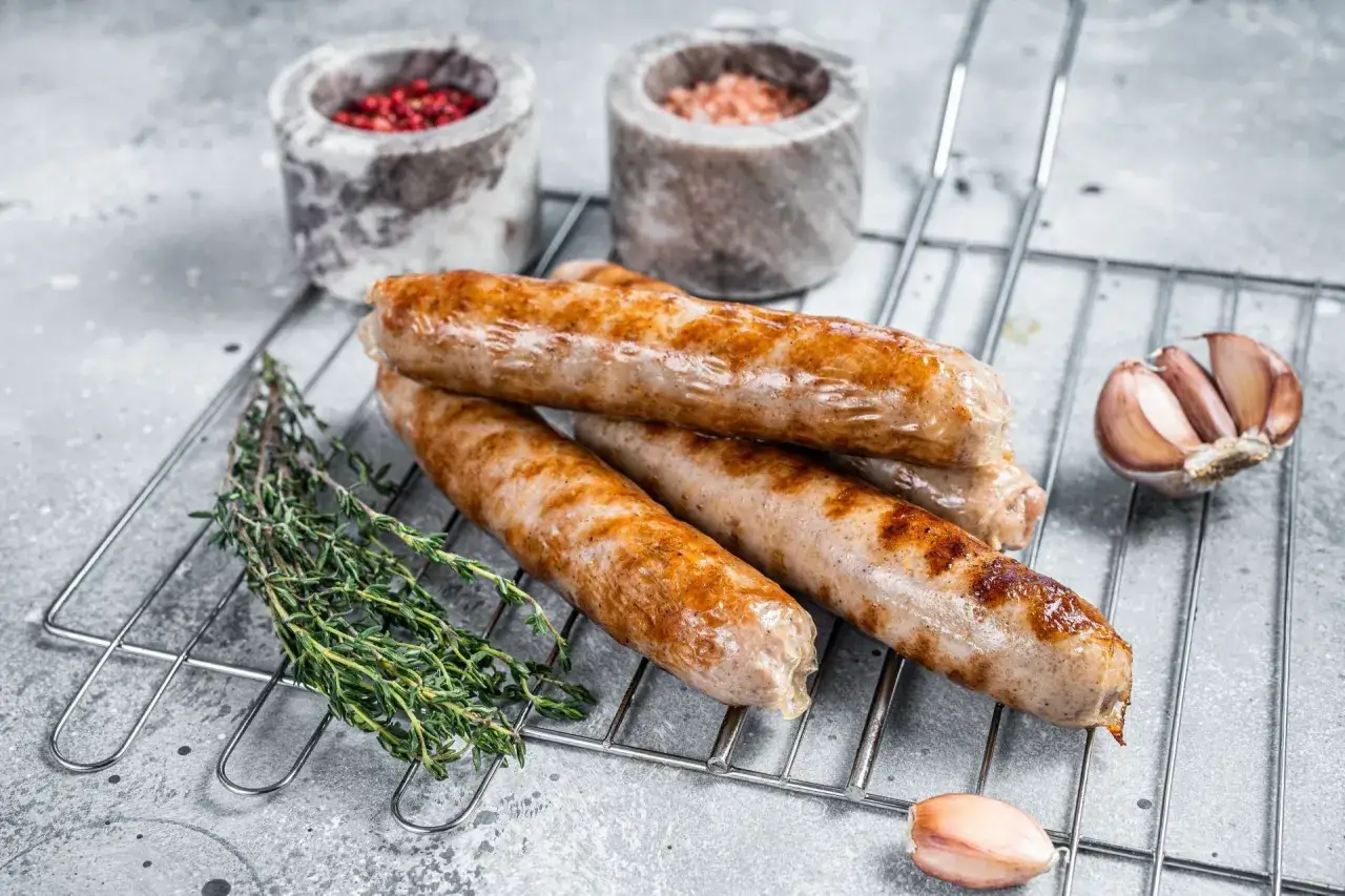 Apetyczna biała kiełbasa z grilla, rumiana i soczysta, z gałązką tymianku i czosnkiem.