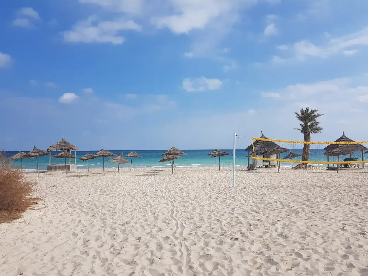 Piękna plaża z parasolami i boiskiem do siatkówki. Idealne miejsce na wakacje, gdzie leży Djerba.