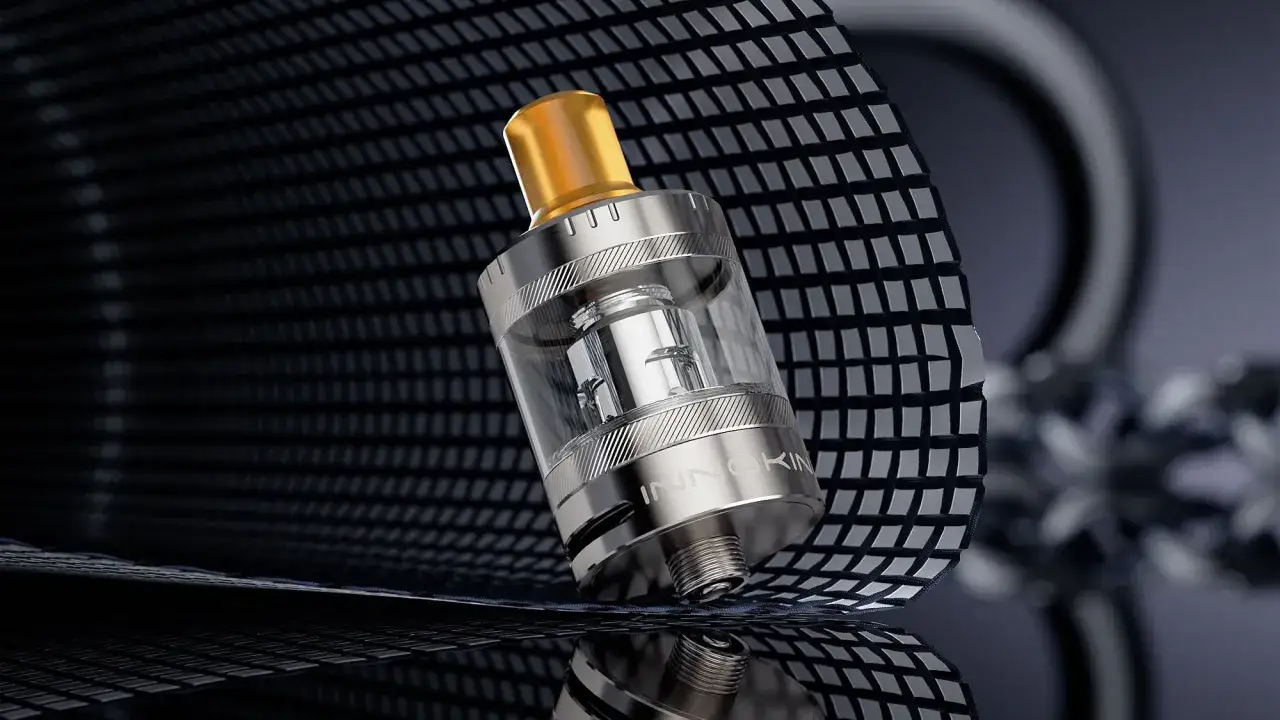 Atomizador metálico con tanque de cristal y un drip tip dorado.