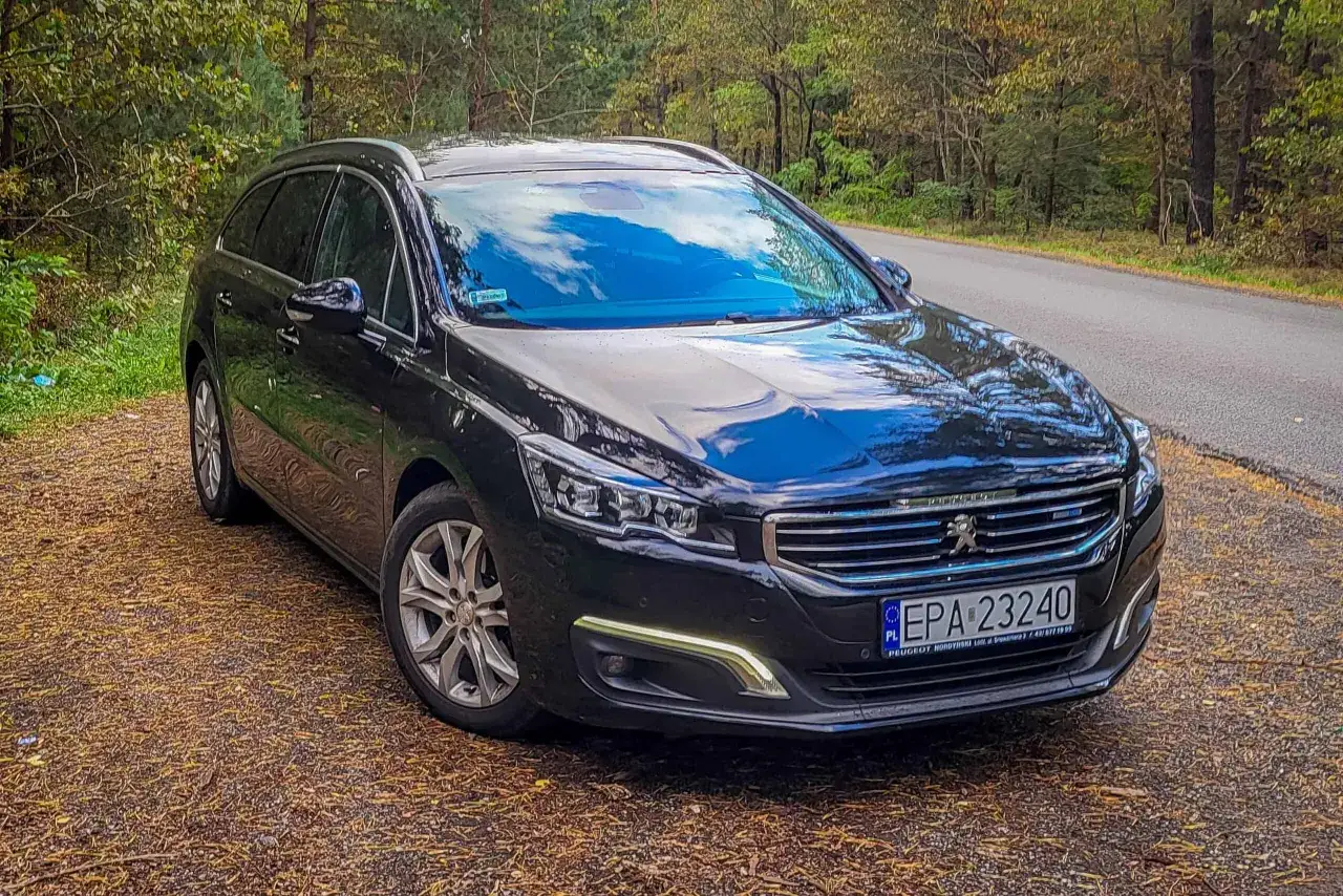 Czarny Peugeot 508 2.0 HDI na leśnej drodze.