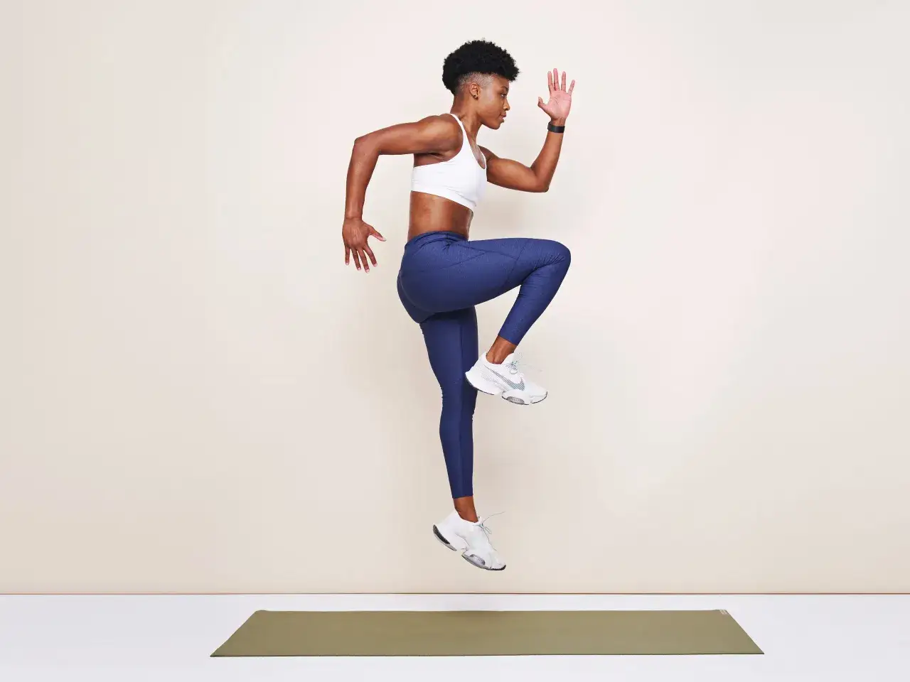 Frau in Sportkleidung macht einen Sprung, Knie hochgezogen. Perfekt f&uuml;r plyometrisches Training zur Steigerung von Kraft und Schnelligkeit.