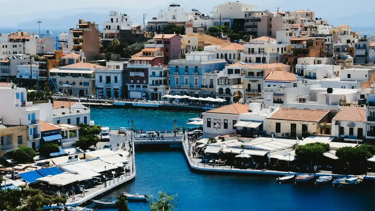 Malowniczy widok na port w Agios Nikolaos na Krecie. Białe budynki, błękitna woda i łodzie tworzą idylliczny krajobraz.