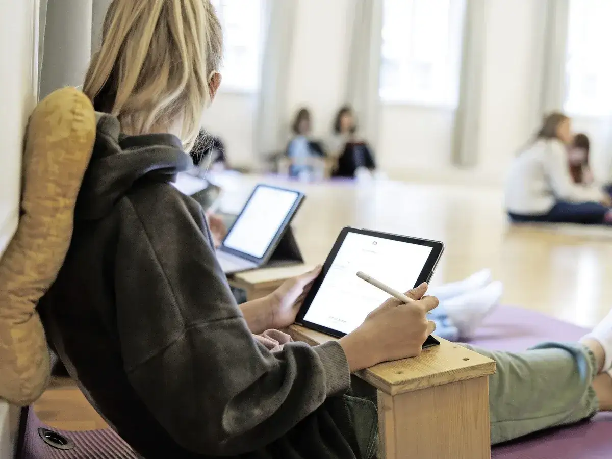 Ein M&auml;dchen lernt mit einer **study smarter app** auf ihrem Tablet. Andere Sch&uuml;ler sind im Hintergrund zu sehen.