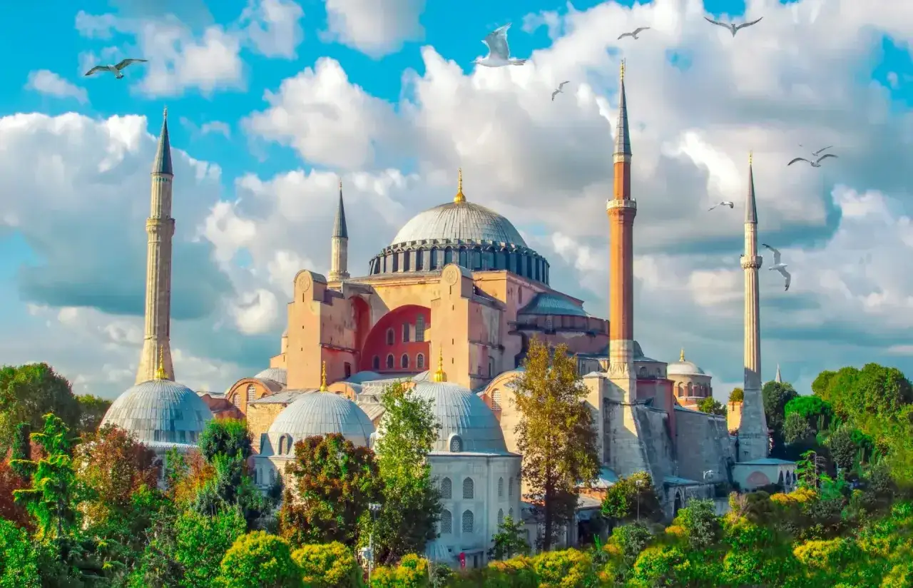 Majestatyczna Hagia Sophia, symbol tego, gdzie jest Stambuł, wznosi się na tle błękitnego nieba z chmurami i mewami.