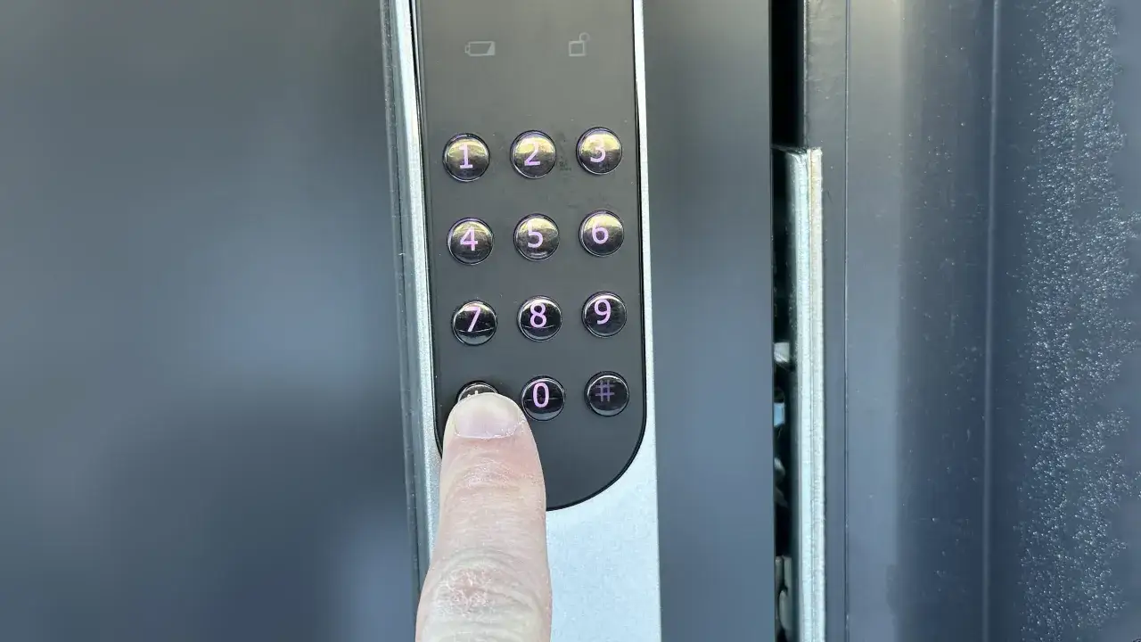 Ett finger trycker på nollan på ett Yale Doorman V2N med app-funktion.